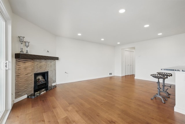 living room featuring recessed lighting, a tile fireplace, baseboards, and light wood-style floors