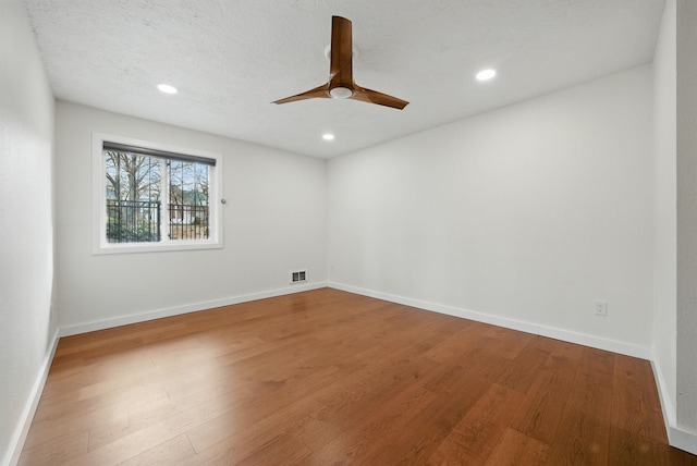 empty room featuring recessed lighting, wood finished floors, visible vents, and baseboards