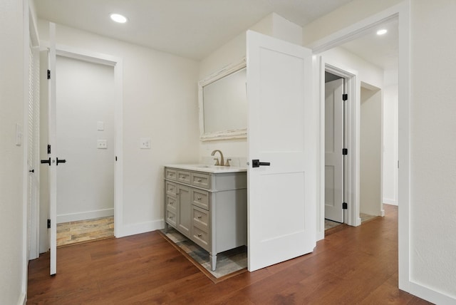 hallway with recessed lighting, baseboards, dark wood-style floors, and a sink