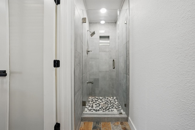 full bath featuring a shower stall and a textured wall