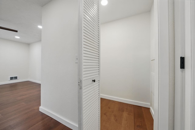 hall featuring dark wood-style floors, visible vents, and baseboards