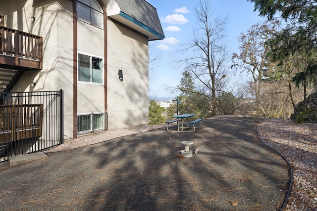 view of home's exterior featuring a shingled roof, a balcony, fence, and stucco siding