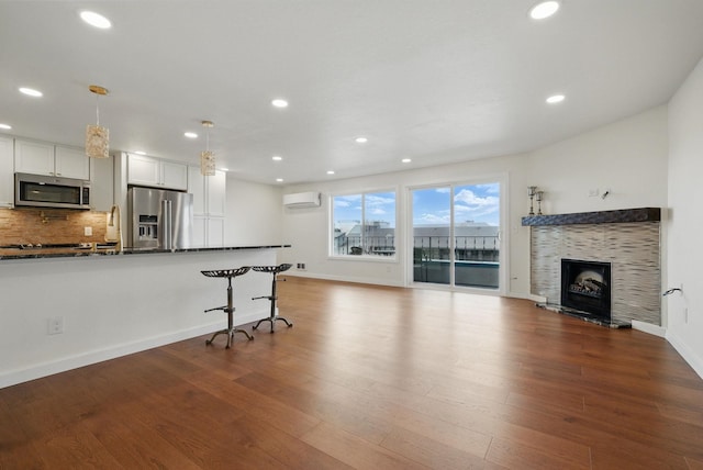 kitchen with a wall unit AC, dark wood-style floors, open floor plan, and appliances with stainless steel finishes