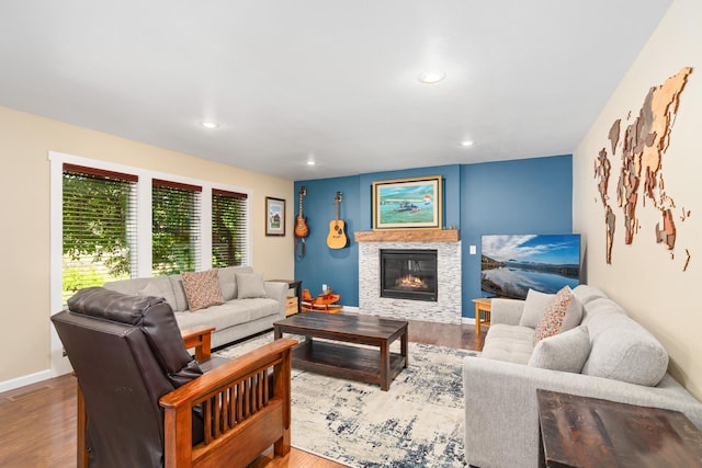 living room featuring a glass covered fireplace, recessed lighting, and wood finished floors