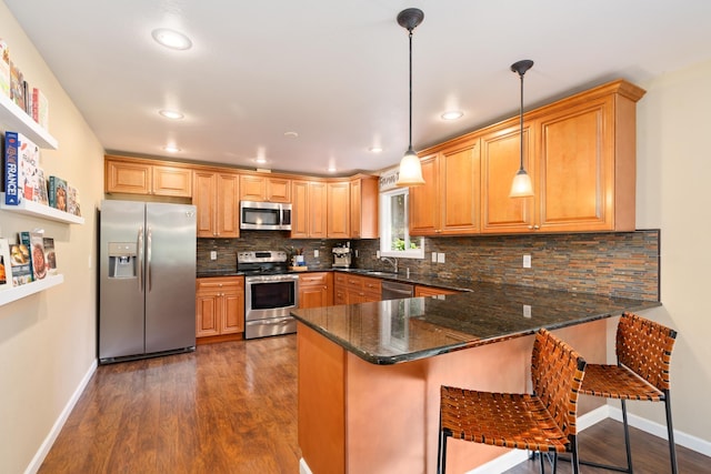 kitchen featuring a peninsula, dark wood-type flooring, appliances with stainless steel finishes, and a sink