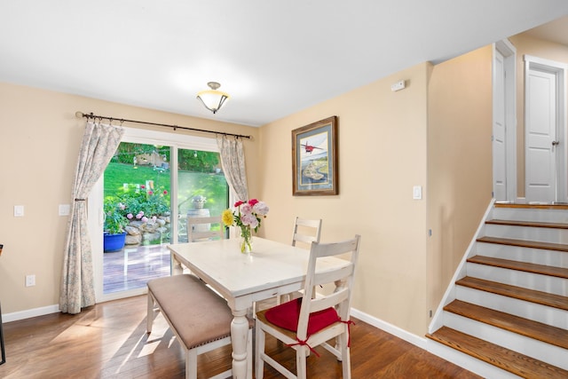 dining space with stairway, baseboards, and wood finished floors