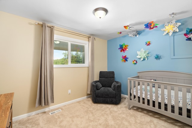 bedroom with a crib, visible vents, baseboards, and carpet floors