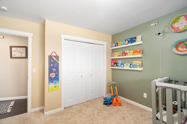 bedroom with a nursery area, carpet flooring, baseboards, and a closet