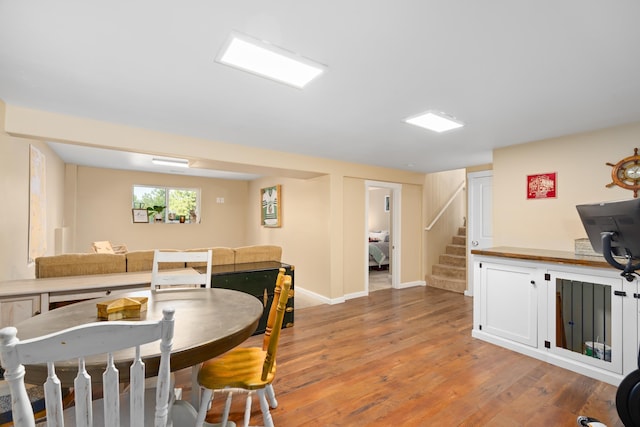 dining room featuring light wood-type flooring, baseboards, and stairs