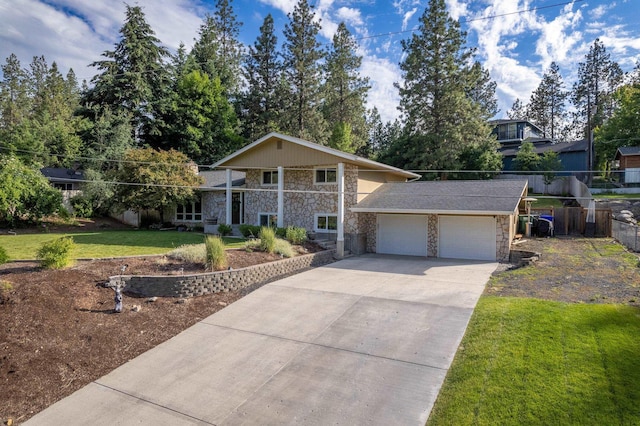 view of front of house with stone siding, an attached garage, concrete driveway, and a front yard