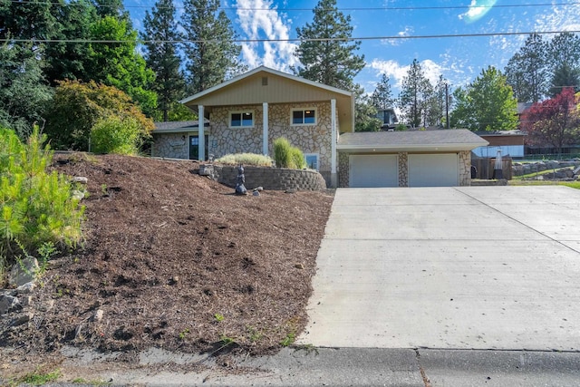 view of front of home featuring stone siding, an attached garage, and concrete driveway