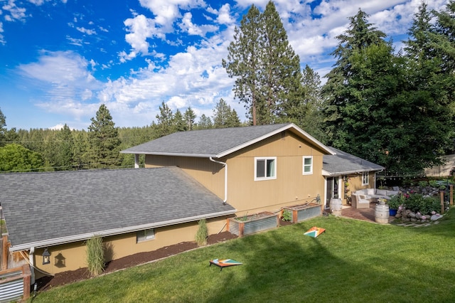 view of side of property with a lawn, roof with shingles, and a garden