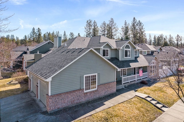 traditional home featuring roof with shingles, a porch, concrete driveway, a garage, and brick siding