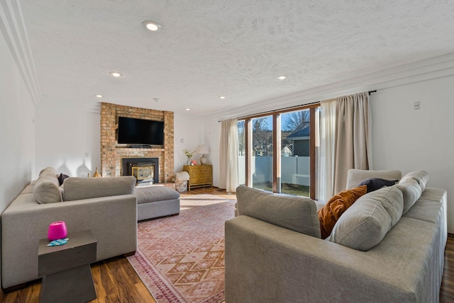 living area with recessed lighting, a textured ceiling, a brick fireplace, and dark wood finished floors