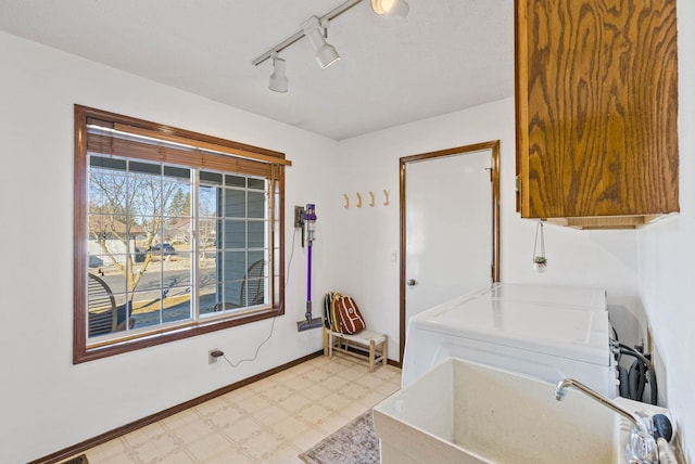 clothes washing area featuring light floors, baseboards, washer / dryer, cabinet space, and a sink