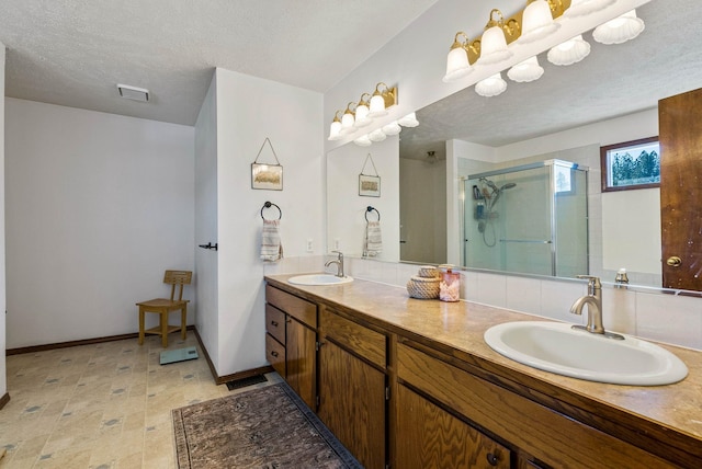 full bath featuring visible vents, a stall shower, a textured ceiling, and a sink