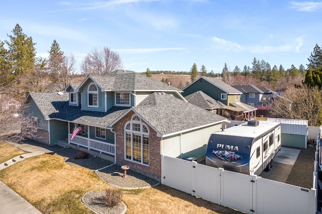 view of front of home featuring brick siding, a shingled roof, fence private yard, covered porch, and a gate