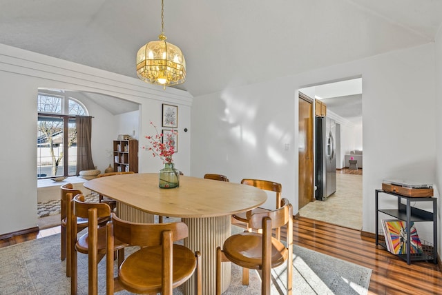 dining space with lofted ceiling, an inviting chandelier, and wood finished floors