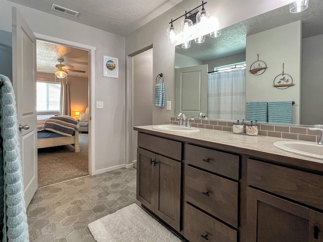 full bath featuring a sink, visible vents, a textured ceiling, and double vanity