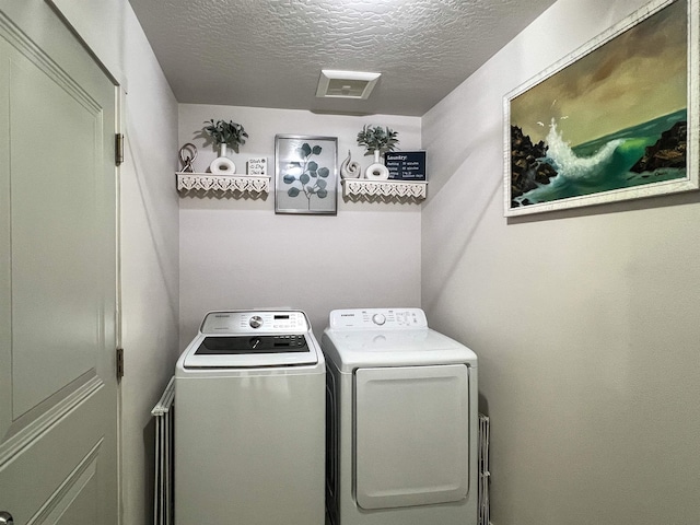 washroom featuring laundry area, independent washer and dryer, a textured ceiling, and visible vents