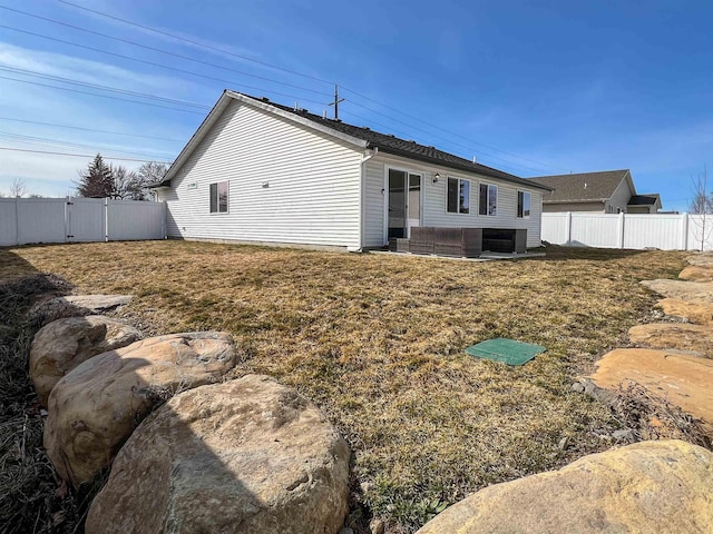 rear view of property with a lawn, a fenced backyard, and a gate