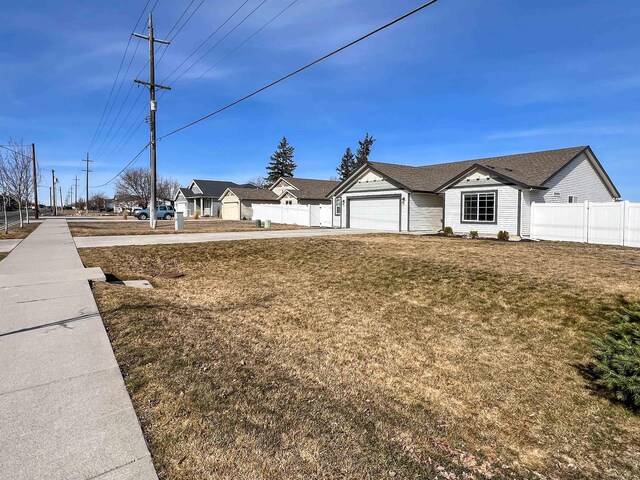 view of yard featuring an attached garage, concrete driveway, and fence