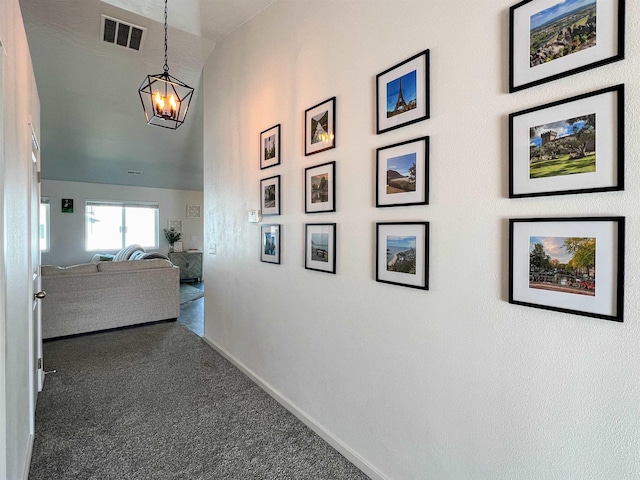 hall featuring visible vents, carpet floors, baseboards, and an inviting chandelier