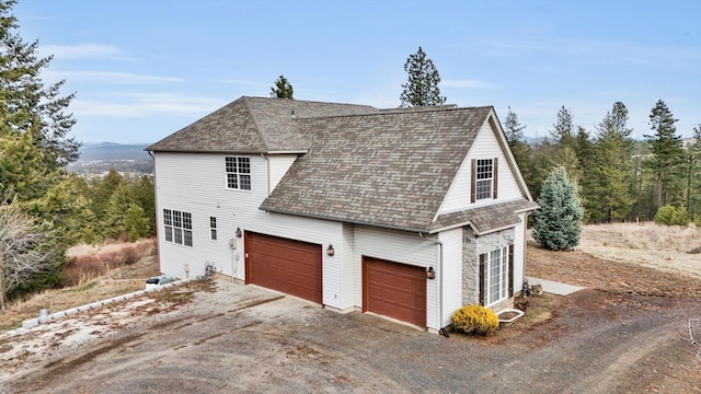 view of property exterior featuring a garage, driveway, and roof with shingles