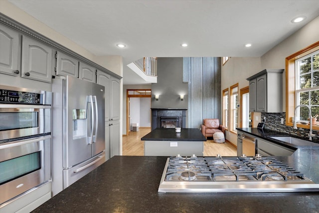 kitchen with a sink, tasteful backsplash, a center island, stainless steel appliances, and a fireplace