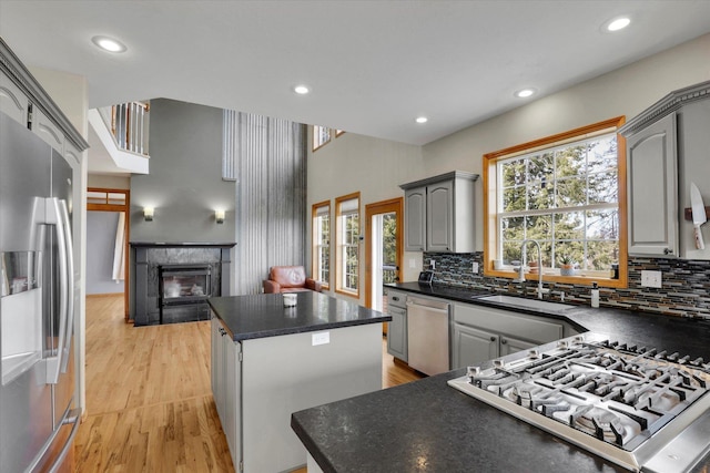 kitchen featuring gray cabinets, a kitchen island, dark countertops, stainless steel appliances, and a fireplace