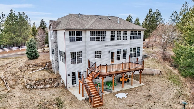 back of property featuring stairway, fence, roof with shingles, a deck, and a patio area