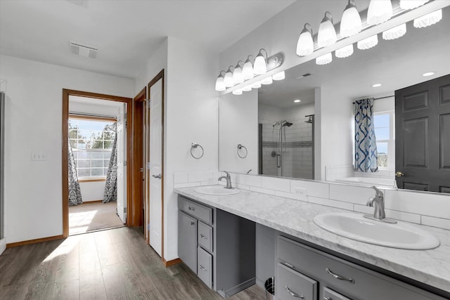 full bath with visible vents, a stall shower, wood finished floors, and a sink