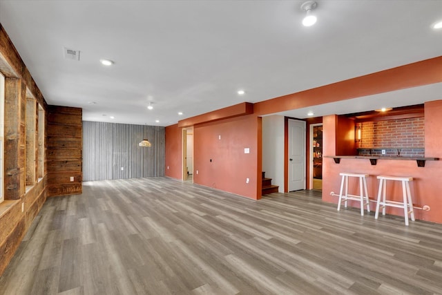 unfurnished living room with stairway, wood finished floors, visible vents, recessed lighting, and a dry bar