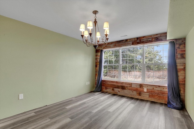 spare room with an inviting chandelier and wood finished floors