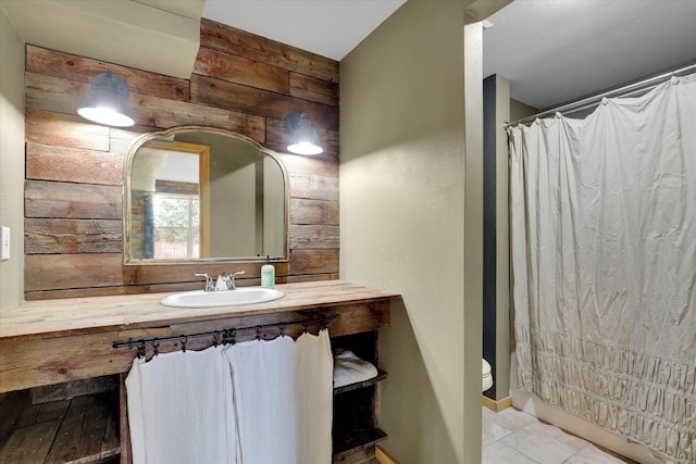 bathroom featuring tile patterned flooring, wood walls, vanity, and toilet