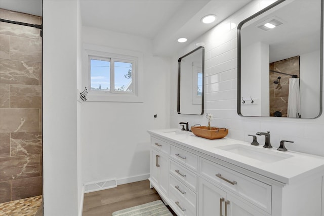 bathroom with visible vents, a tile shower, and a sink