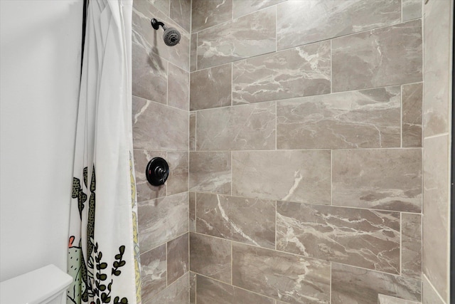 bathroom featuring toilet and a tile shower