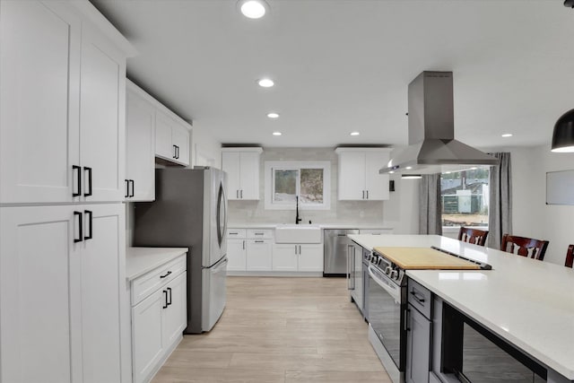 kitchen with a sink, light countertops, island exhaust hood, and stainless steel appliances