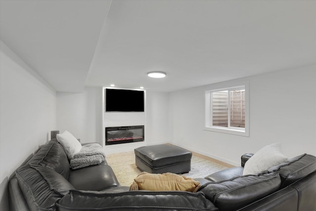 living area with wood finished floors, baseboards, and a glass covered fireplace