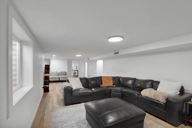 living room featuring light wood finished floors, visible vents, and baseboards