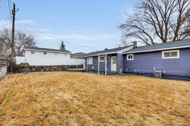 back of property featuring fence, entry steps, cooling unit, a chimney, and a yard