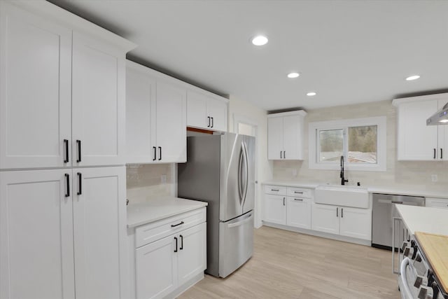 kitchen with light countertops, white cabinets, appliances with stainless steel finishes, and a sink