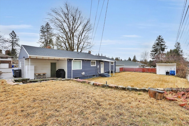 back of house featuring an outbuilding, a yard, fence, and a chimney