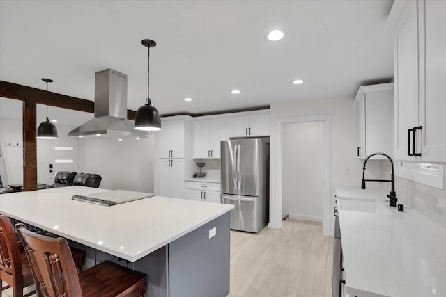 kitchen featuring light wood-style flooring, island exhaust hood, freestanding refrigerator, a sink, and light countertops