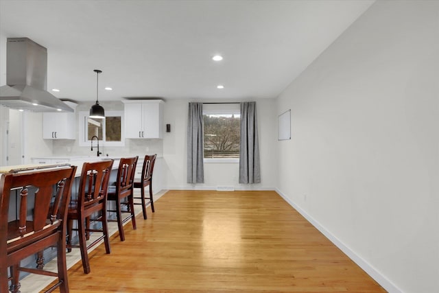 dining space with light wood-style flooring, recessed lighting, and baseboards