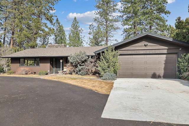 ranch-style house featuring concrete driveway, an attached garage, and a shingled roof