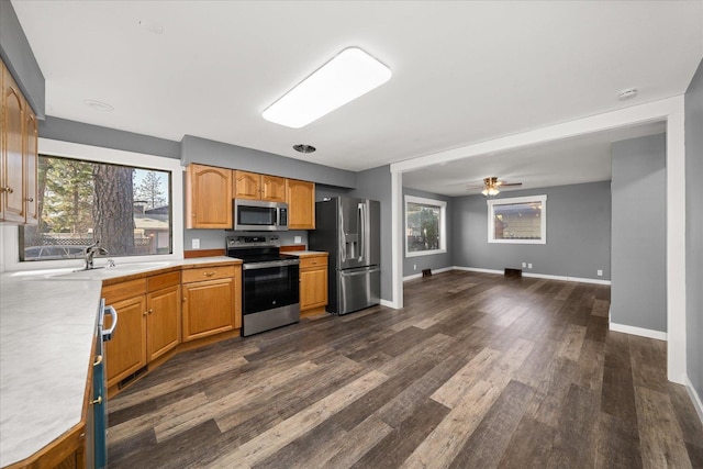 kitchen with a sink, dark wood finished floors, stainless steel appliances, light countertops, and baseboards