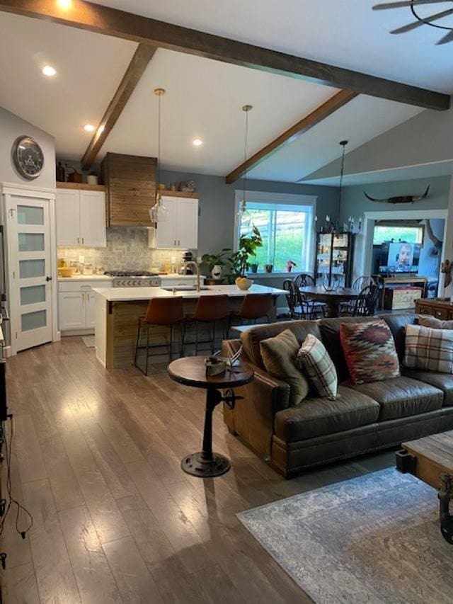 living area with lofted ceiling with beams and wood finished floors