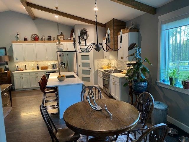 dining area featuring an inviting chandelier, vaulted ceiling with beams, baseboards, and wood finished floors