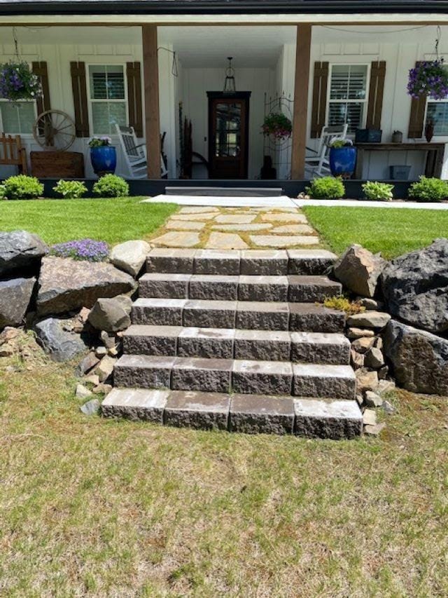 entrance to property with a lawn and covered porch